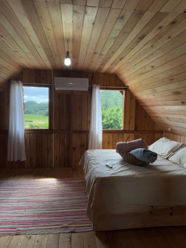 ein Schlafzimmer mit einem Bett in einem Holzhaus in der Unterkunft Casa de Campo no Oliveira in Tijucas