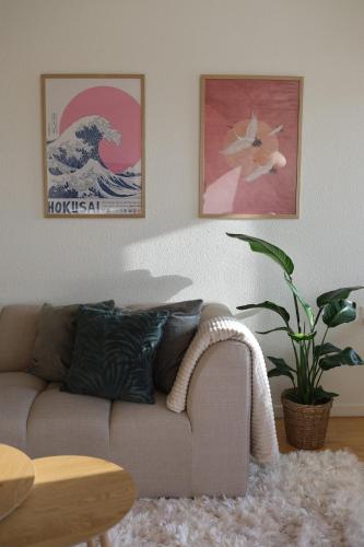 a living room with a couch and a painting of a wave at Cosy appartment near city, beach, metro & airport in Copenhagen