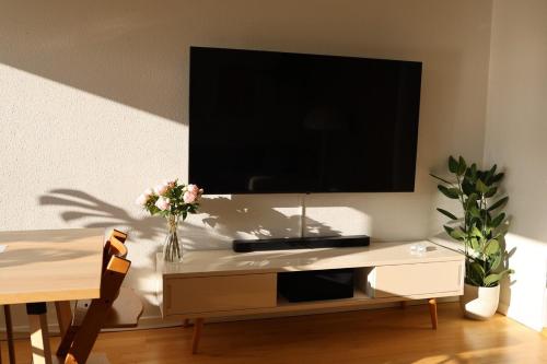 a tv on a wall with a table with flowers at Cosy appartment near city, beach, metro & airport in Copenhagen