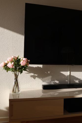 a vase of flowers on a table next to a tv at Cosy appartment near city, beach, metro & airport in Copenhagen