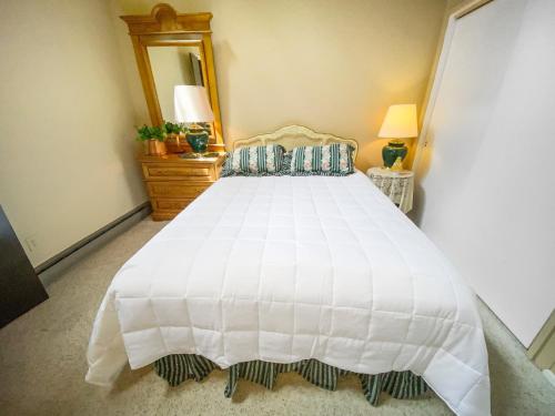 ein Schlafzimmer mit einem großen weißen Bett und einem Spiegel in der Unterkunft Fairway View in Sisters