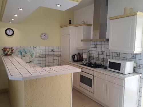 une cuisine avec des armoires blanches et un micro-ondes dans l'établissement Gîte de Louis - Terrasse - Centre de Domme, à Domme