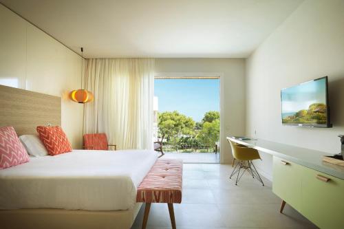 a bedroom with a bed and a desk and a window at Inturotel Cala Esmeralda Beach Hotel & Spa - Adults Only in Cala d´Or