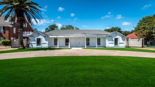 a white house with a palm tree and a driveway at Poolside Opulence Tennis and HotTub in Corpus Christi