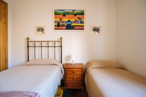 a bedroom with two beds and a dresser and a picture at Casa Centrtrica Umbrete in Umbrete
