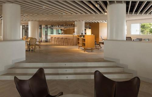 a lobby with chairs and tables in a building at Inturotel Cala Esmeralda Beach Hotel & Spa - Adults Only in Cala d´Or