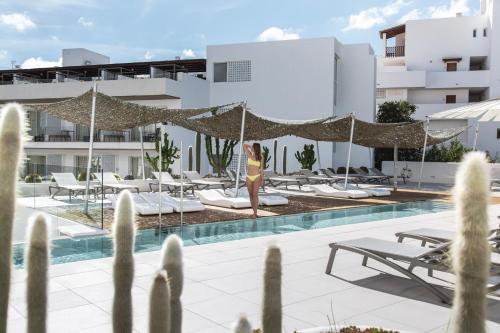 a woman standing next to a pool at a hotel at Inturotel Cala Esmeralda Beach Hotel & Spa - Adults Only in Cala d´Or