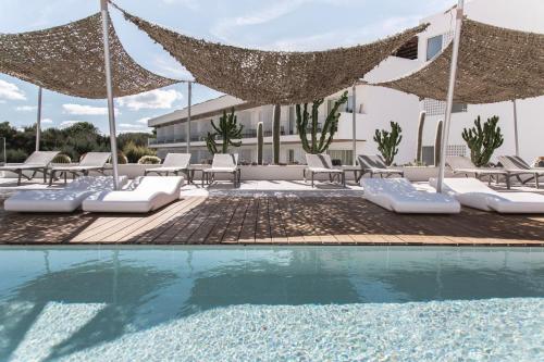a pool with chairs and umbrellas next to a building at Inturotel Cala Esmeralda Beach Hotel & Spa - Adults Only in Cala d´Or