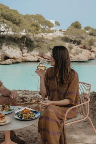 a woman sitting at a table with a plate of food at Inturotel Cala Esmeralda Beach Hotel & Spa - Adults Only in Cala d´Or