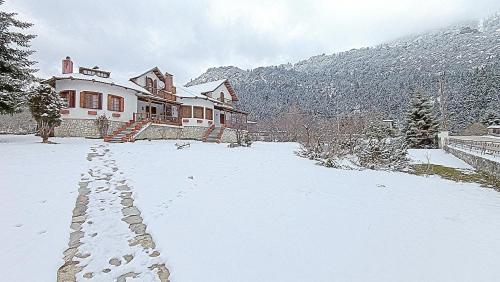 a house with snow on the ground in front of it at Woodman’s home in Vlatanéoi