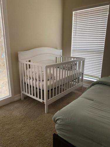 a white crib in a bedroom with a window at The Ultimate Staycation in San Antonio