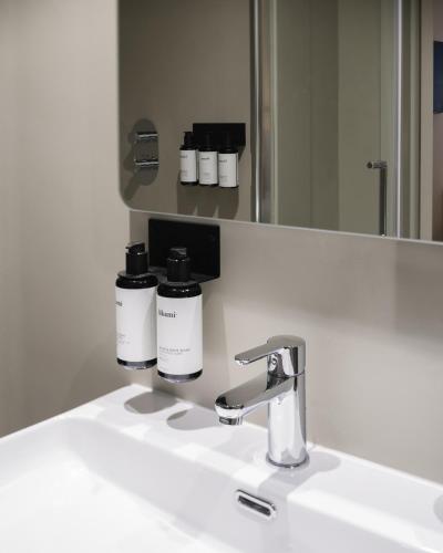 a bathroom sink with two bottles of moisturizers on it at Lits de Lo - Boutique Rooms in Ghent