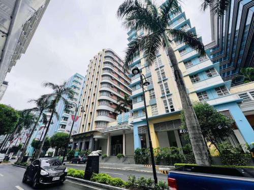 a car parked in front of a building with palm trees at A&G Condotel at 101newport Near NAIA T3 in Manila