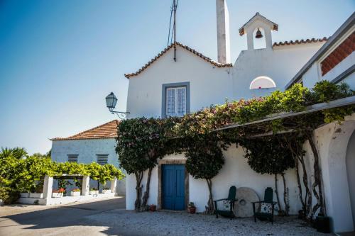 a white building with a blue door and vines at Quinta do Piloto in Palmela