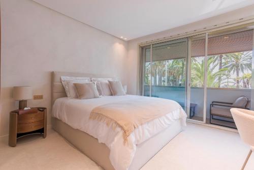 une chambre blanche avec un lit et une grande fenêtre dans l'établissement La Réale Croisette, à Cannes