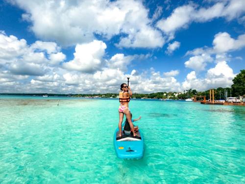 a woman on a paddle board in the water at Hotel & Eco Cabañas Azul María Bacalar- Gratis Club de playa in Bacalar