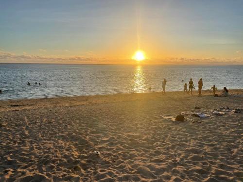 a group of people on the beach at sunset at Chambre lit double à 3 mins à pied du Lagon Salines les bains in La Saline les Bains