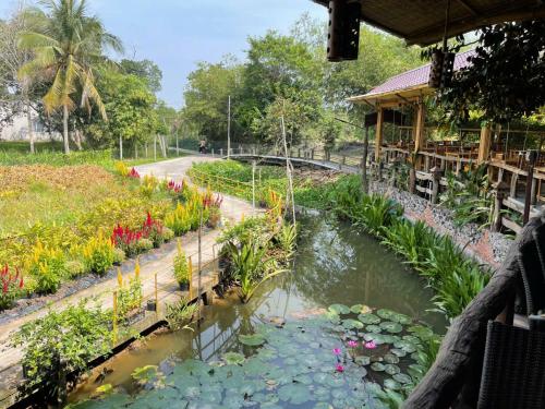 a garden with a pond and flowers at Bamboo Eco Village in Can Tho