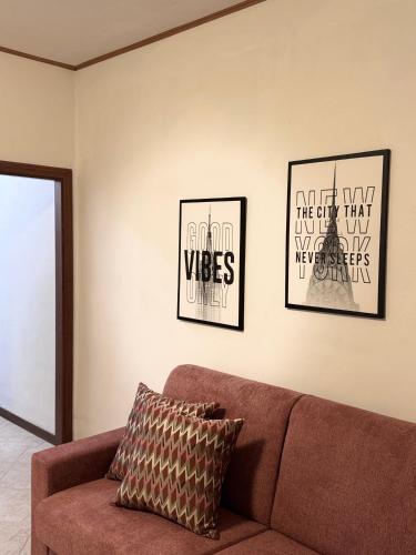 a living room with a brown couch and two posters at Villa dei Macchini in Chiusi della Verna