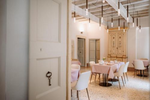 a dining room with a table and white chairs at Wine Relais Villa Cipolla Pieropan in Tregnago