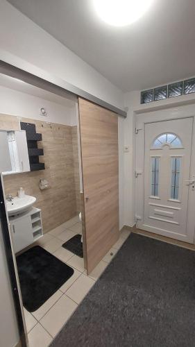 a bathroom with a door and a sink and a toilet at Holiday Apartman in Mórahalom