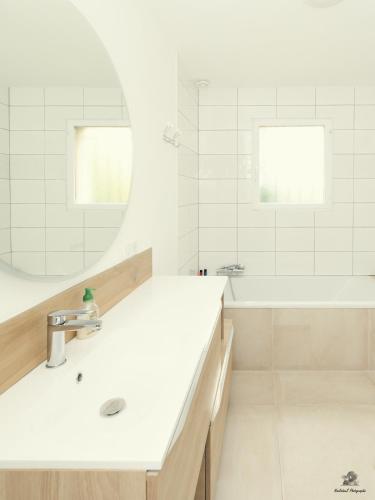 La salle de bains blanche est pourvue d'un lavabo et d'une baignoire. dans l'établissement Maison des viennes, à Saint-André-les-Vergers