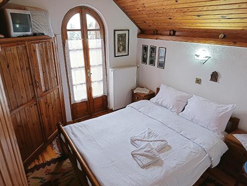 a bedroom with a white bed with a wooden ceiling at Woodman’s home in Vlatanéoi