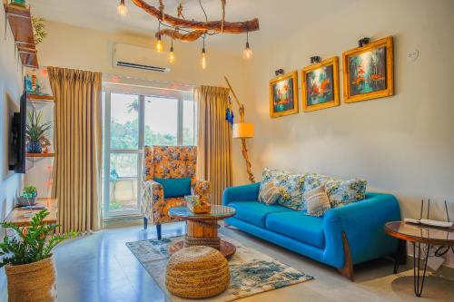 a living room with a blue couch and a table at Alaya Stays 2 BHK with Balcony & Lift - Veera Marina in Goa