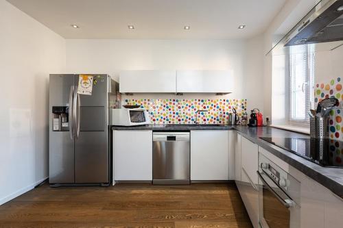 une cuisine avec des armoires blanches et des appareils en acier inoxydable dans l'établissement Un havre de Charme Proche Strasbourg, à Handschuheim