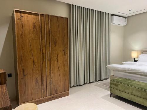 a bedroom with a large wooden cabinet next to a bed at سويت بغرفة نوم وصالة جانبية in Hail