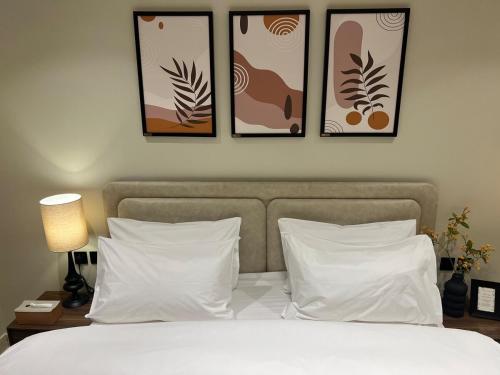 a bedroom with three pictures above a bed with white pillows at سويت بغرفة نوم وصالة جانبية in Hail