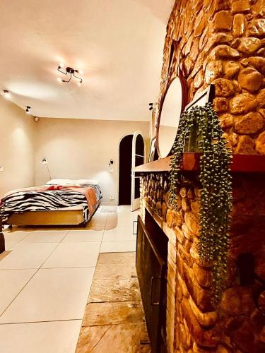 a bedroom with a bed and a stone wall at Pousada Casinha Amarela - Campos do Jordão in Campos do Jordão