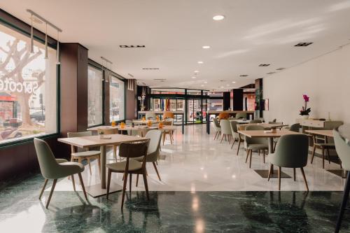 a restaurant with tables and chairs and windows at Sercotel Amistad Murcia in Murcia
