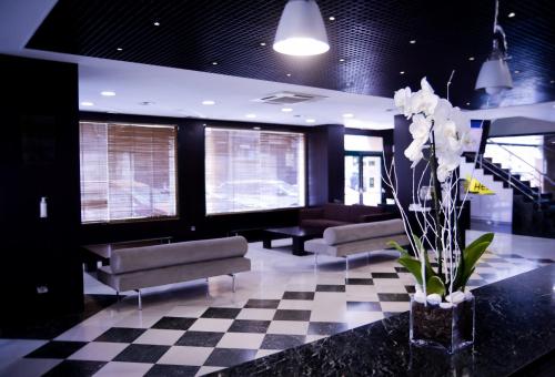 a lobby with couches and flowers on a checkered floor at Sercotel Amistad Murcia in Murcia
