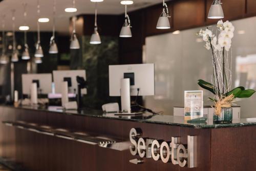 a lobby with a reception counter with flowers on it at Sercotel Amistad Murcia in Murcia