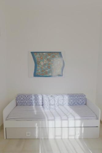 a white bed in a room with a painting on the wall at Goccia Perla - Gocce sul Mare in Torre Canne