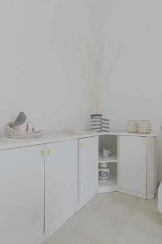 a kitchen with white cabinets and a white wall at Goccia Perla - Gocce sul Mare in Torre Canne