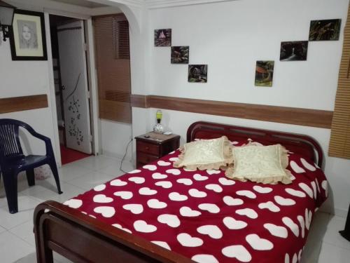 a bedroom with a red bed with white pillows at Hostal las margaritas in Pasto