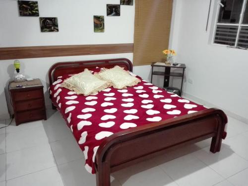 a bed with a red and white comforter in a room at Hostal las margaritas in Pasto