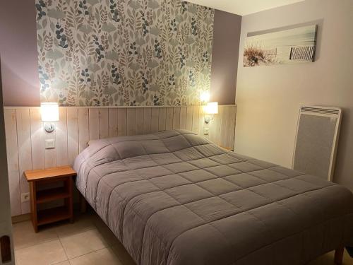 1 dormitorio con cama y pared con papel pintado en Appartement Moliets Plage Golf, en Moliets-et-Maa