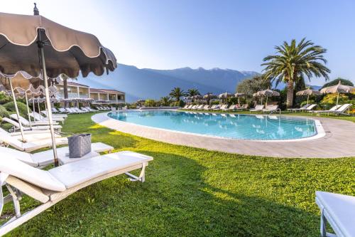 a pool at a resort with lawn chairs and umbrellas at Park Hotel Imperial in Limone sul Garda