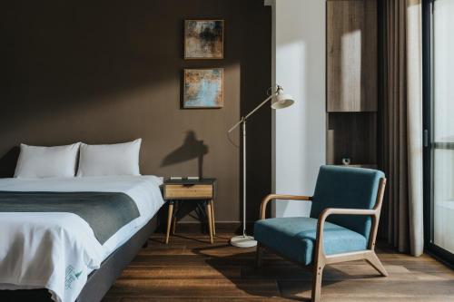 a bedroom with a bed and a chair and a lamp at Yanyu Yuchi BY REINDEER in Yuchi