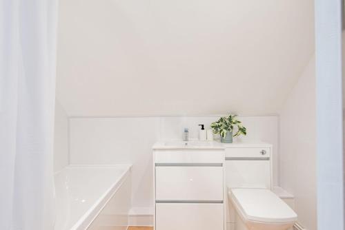 a white bathroom with a toilet and a sink at The Old Barn in Sandwich