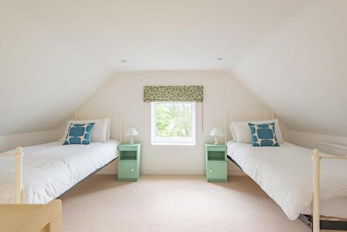 two beds in a room with a window at The Old Barn in Sandwich