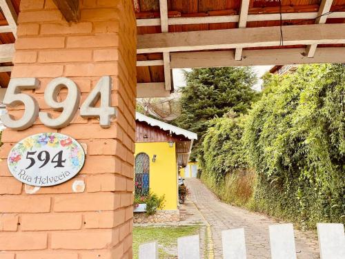 a sign on the side of a brick building with a sign at Pousada Casinha Amarela - Campos do Jordão in Campos do Jordão