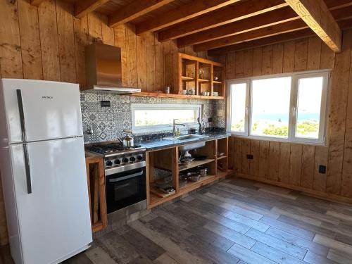 a kitchen with a refrigerator and a stove at Cabañas Lodge Puerta Roja in Los Helechos