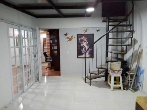 a living room with a staircase and birds on the wall at Hostal las margaritas in Pasto