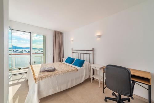 a bedroom with a desk and a bed with blue pillows at Windsong in Port de Pollensa