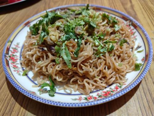 a plate of food with noodles on a table at Dawn Home Stay in Darjeeling