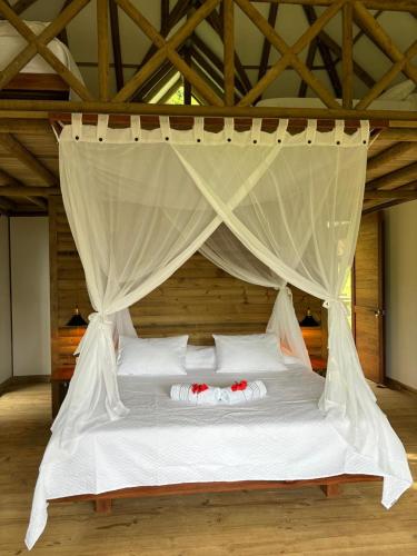 a bed with a canopy with two pillows on it at Jenené Lodge Nuquí in Nuquí